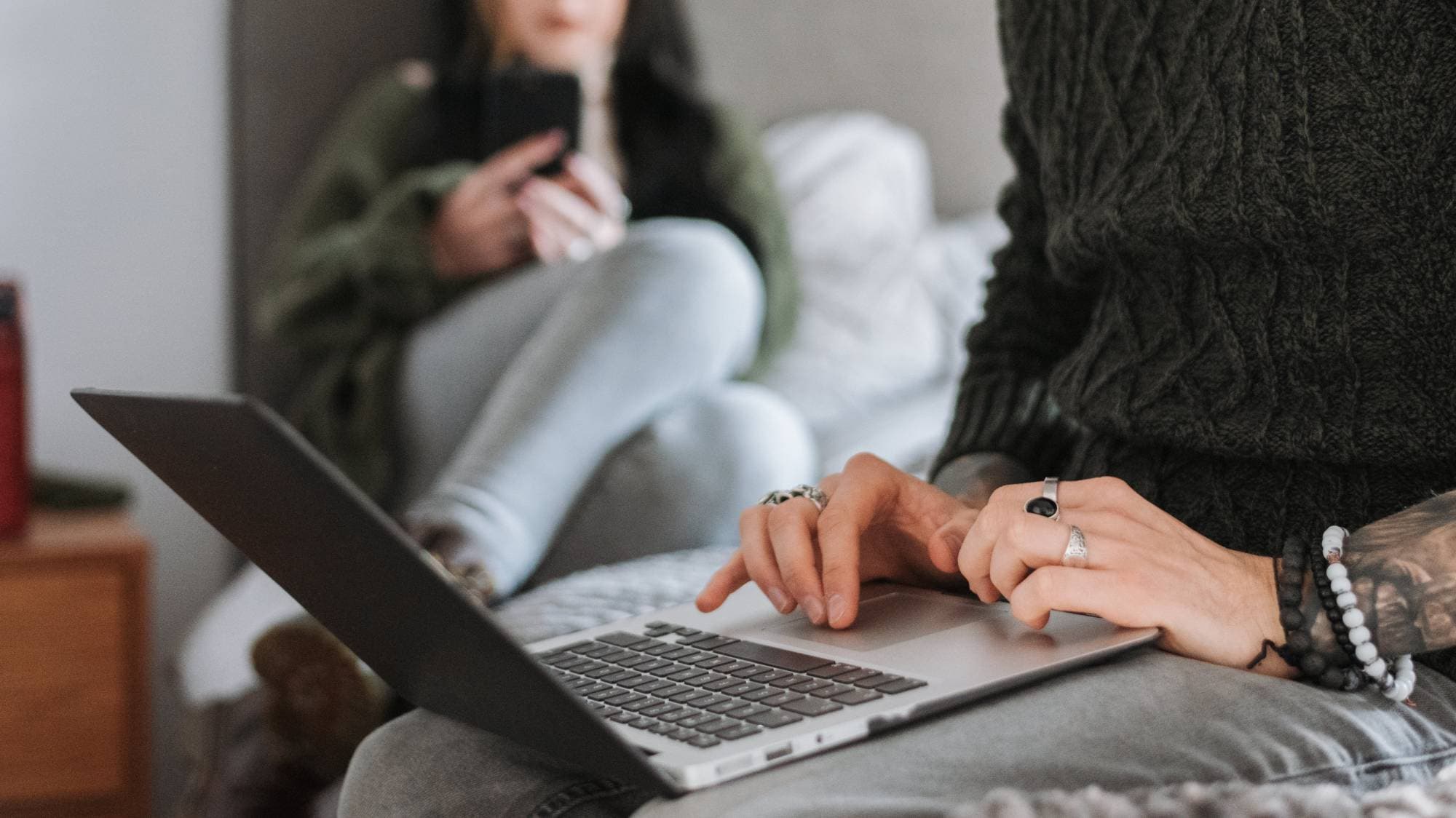 person sitting on a bed, using a macbook